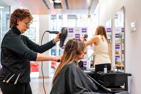 Professional hairdresser using a blow dryer to style a customer's hair, providing expert beauty and