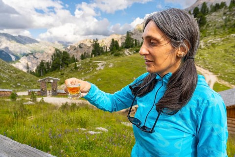 Close up woman traveler drinking local herbal spirit schnapps or grappa shot glass wooden terrace