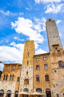 Towers of the old Town with historic buildings from Piazza del Duomo at San Gimignano on a sunny