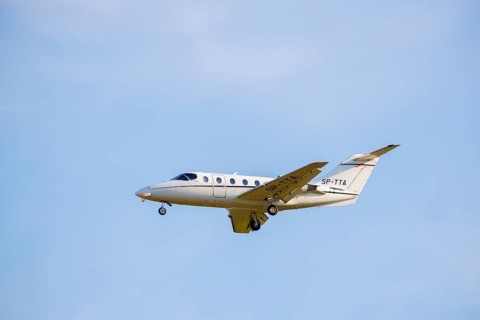 A white private jet flying through the blue sky, clearly visible, light jet, Hawker 400 XP