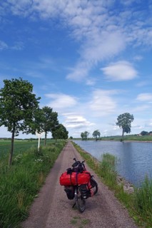 Relaxing bike trip along a narrow path next to a canal under a clear sky, Götaleden, Göta Canal,