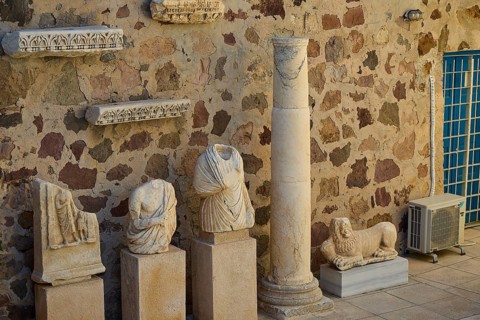 Plaka Archaeological Museum, ancient sculptures and a column in front of a stone wall in an