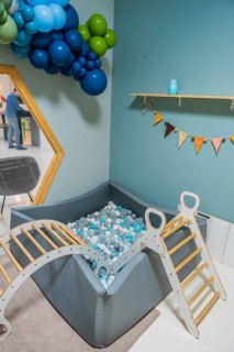 Modern daycare interior with a colorful soft play ball pit, wooden climbing frame and vibrant