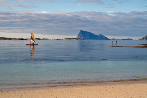 A quiet beach, a small sailboat and islands on the horizon under a cloudy sky, calendar picture,