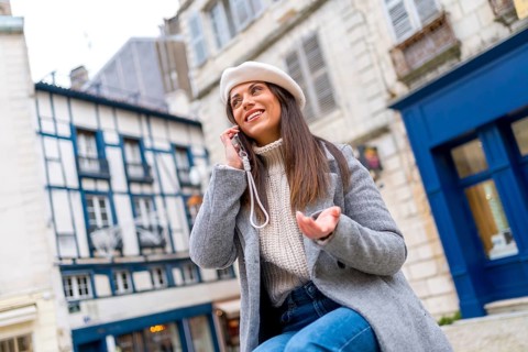 Woman with french style clothes talking to the mobile sitting in the street