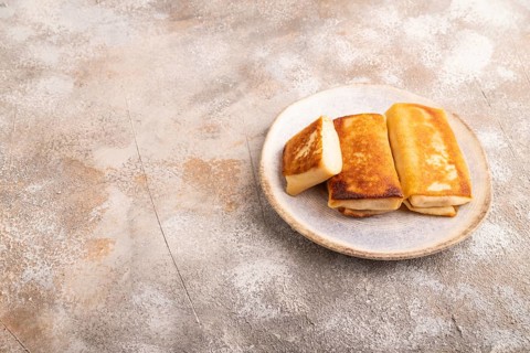 Fried crispy pancakes with meat and cheese on brown concrete background. side view, copy space