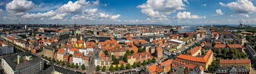 Weitläufige Stadtansicht mit roten Dächern unter blauem Himmel mit Wolken, Kopenhagen, Dänemark,