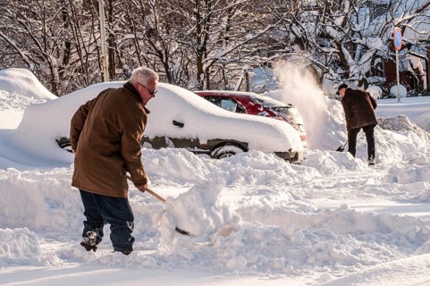 Winter, two men clearing snow from cars in parking lot in Ystad, Skåne County, Sweden, Scandinavia