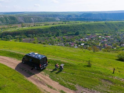 Motorhome parked on a street with a wide view over green hills, aerial view, camper, view of