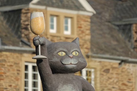 Zeller Schwarze Katz holding up with wine glass, symbol of wine and wine-growing region, gray cat