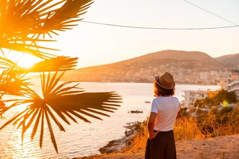 Tourist woman at Sarande or Saranda sunset in Albanian riviera enjoying summer vacation, Albania