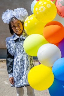 Happy schoolgirl with colourful balloons on the first day of school, Issyk-Kul region, Kyrgyzstan