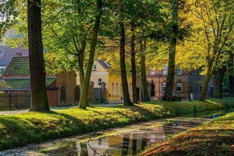 Autumn coloured trees in a park at the river Nieplitz, behind them old brick houses,