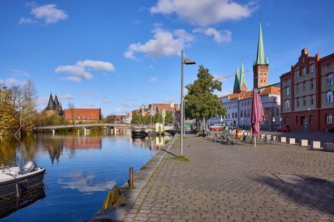 River Trave with quay wall, lantern, pedestrian bridge Obertravebrücke, Holstentor, church towers