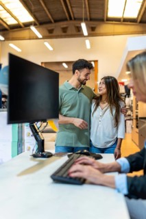 Young couple standing at a customer service desk in a home improvement store, consulting with an