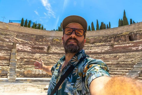 Man taking a selfie, enjoying travel and tourism while discovering the historic roman theatre