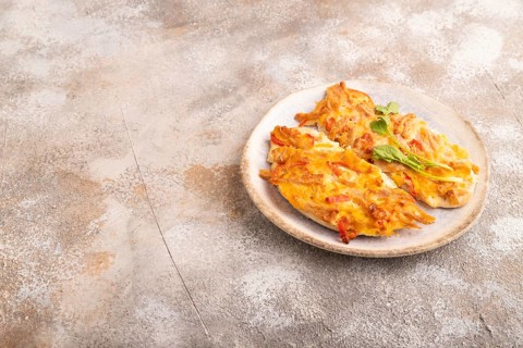 Baked chicken meat with cheese and tomatoes on brown concrete background. side view, copy space