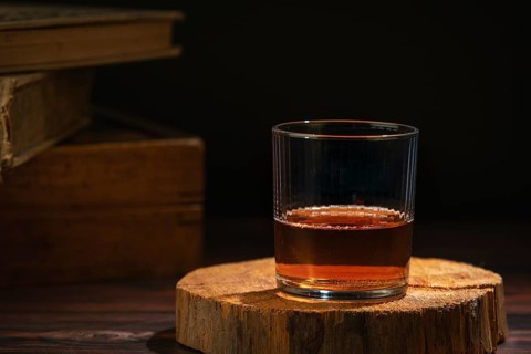 Glass of whiskey on a rustic wooden slice in a cozy atmosphere