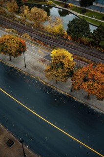 Aerial view of a quiet urban asphalt road in Montreal, lined with colorful autumn trees. A railway