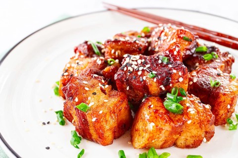 Chinese-style meat with sesame seeds and green onions, on a white plate, marble table, homemade, no