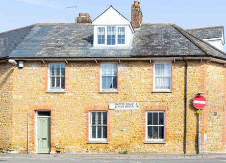Vintage listed road distance mileplate sign historic old stone building, Fore Street, Castle Cary,