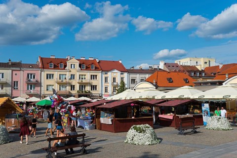 Colourful market square with stalls, people and historic buildings in the sunshine, Bialystok,