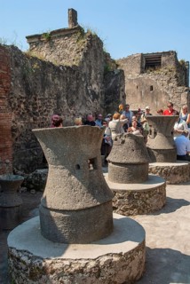 Tourists at bakery oven and grain mills in the archeologic site of Pompei, UNESCO World Heritage