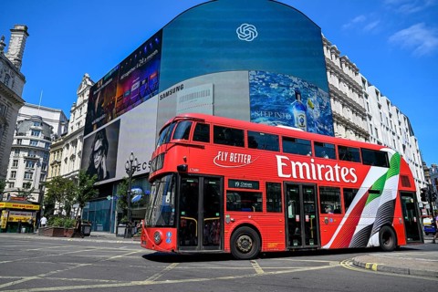 Red double-decker bus in front of digital billboards at Piccadilly Circus, City of Westminster,