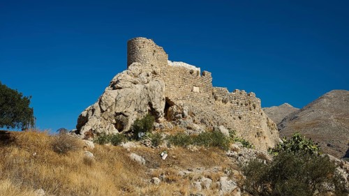 Kastro, Chrisocherias monastery, old castle ruins on a rocky hill under bright blue sky, Pothia,