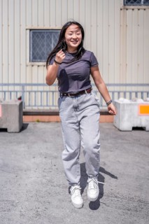 Vertical photo of a K-pop female happy asian dancer jumping dancing in an industrial outdoor space