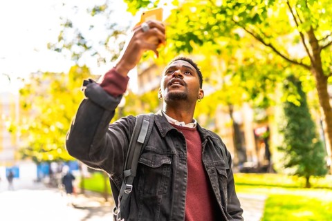 African man visiting a city taking photos with a mobile phone during sunset