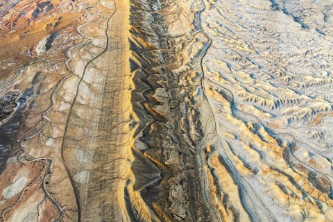 A stunning aerial view of Utah's golden sandstone desert highlights intricate geological patterns