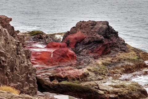 Red and black rocks jutting into the sea on a rugged coastline, Playa Blanca