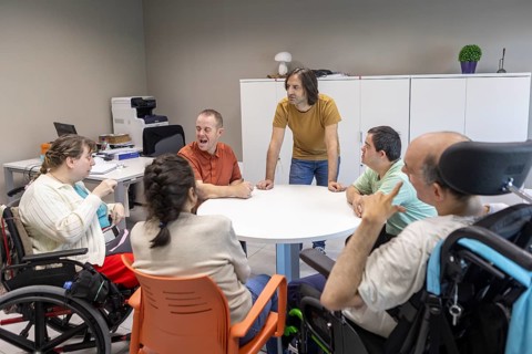A group of individuals with mental disabilities participate in a discussion with a caregiver at a