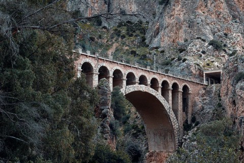Historic viaduct in a rocky, wooded landscape on the Caminito del Rey path, Malaga, Spain