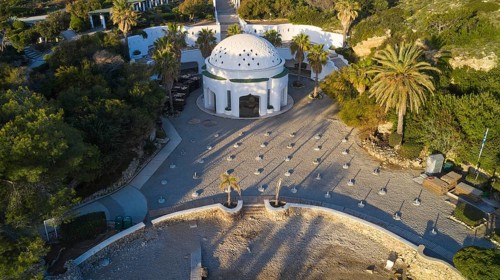 Drone shot, morning light, White building with dome and arched windows, surrounded by palm trees on