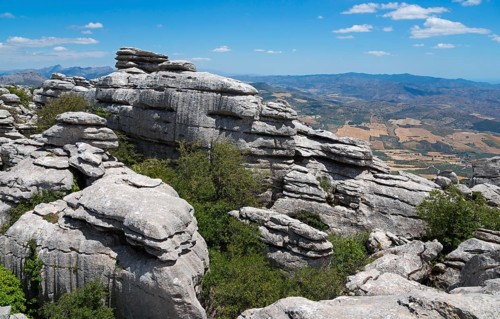 High cliffs and mountain landscape under a clear blue sky, in the background wide fields and