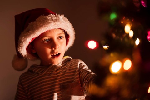 Portrait of 8 years old boy decorating Christmas tree