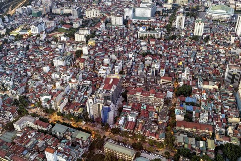 Dense collection of buildings in a city at dusk, the skyscrapers protrude between the residential