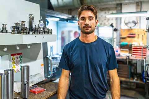 Portrait of a young manual worker in a cnc factory standing looking at the camera