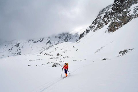 Ski tourer in wintry mountain landscape with cloudy mountain peaks, ascent to Piz Laviner, Grisons