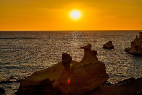 Sunset, sunny horizon over quiet lake with dark rocks in foreground, Aspragremna, white cliffs,