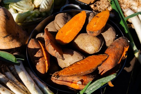 Close-up of fresh calsots and sliced sweet potatoes ready for a traditional Catalan calsotada.