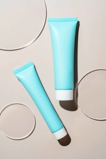 Blue cosmetic tubes artfully placed on a smooth surface, featuring soft shadows and circular