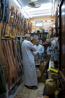 Omani men in dishdasha in the gun shop in the souk or soug or market, old town, Nizwa,