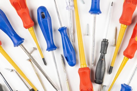 Various colorful screwdrivers and screws on white background