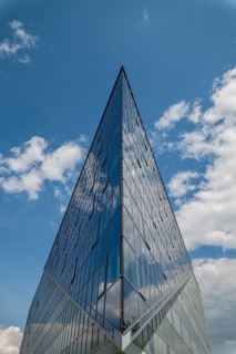 Triangle glass building with reflection of clouds in the windows