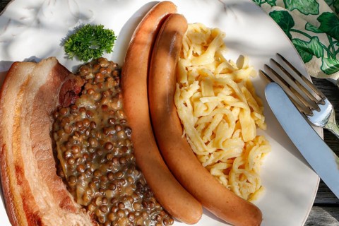 Swabian cuisine, lentils with spaetzle, pancetta and string sausages, meat arranged on a plate,