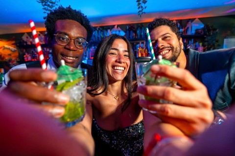 Cheerful multi ethnic friends enjoying cocktails at a vibrant bar, celebrating the weekend