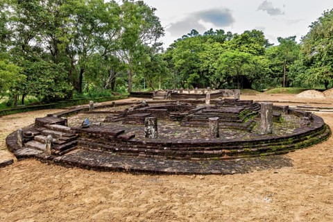 Circular stone complex with remains of columns, surrounded by greenery, temple ruins near Sigiriya